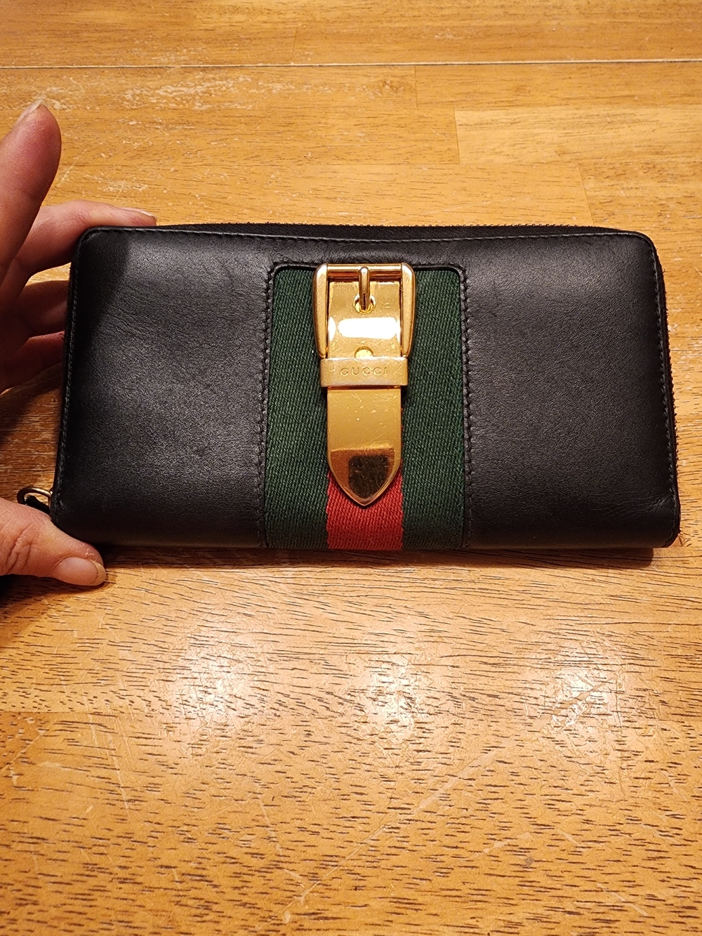 black leather Gucci Sylvie zip-around wallet featuring iconic red & green Web